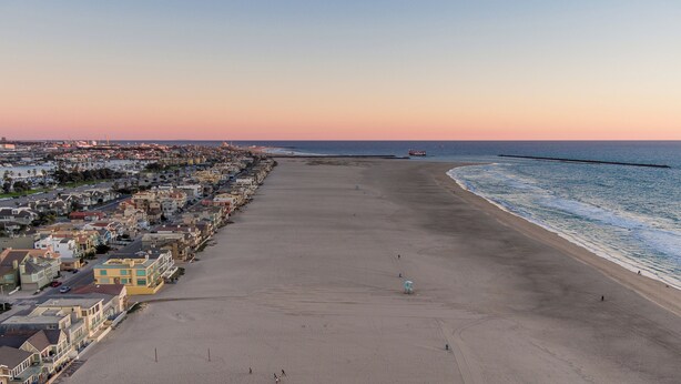 A coastal town with a long sandy beach, rows of houses, and a pier extending into the water. - Historic "Spanish Jewel" at HOLLYWOOD BEACH (Oxnard)