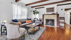 A living room with a fireplace, a sofa, a chair, and a coffee table. - Historic "Spanish Jewel" at HOLLYWOOD BEACH (Oxnard)