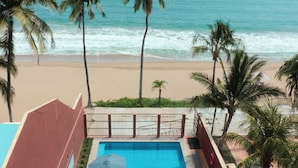 A rooftop pool with a view of the beach and ocean, surrounded by palm trees and lounge chairs. - HOTEL AURELIA (San Patricio Melaque)