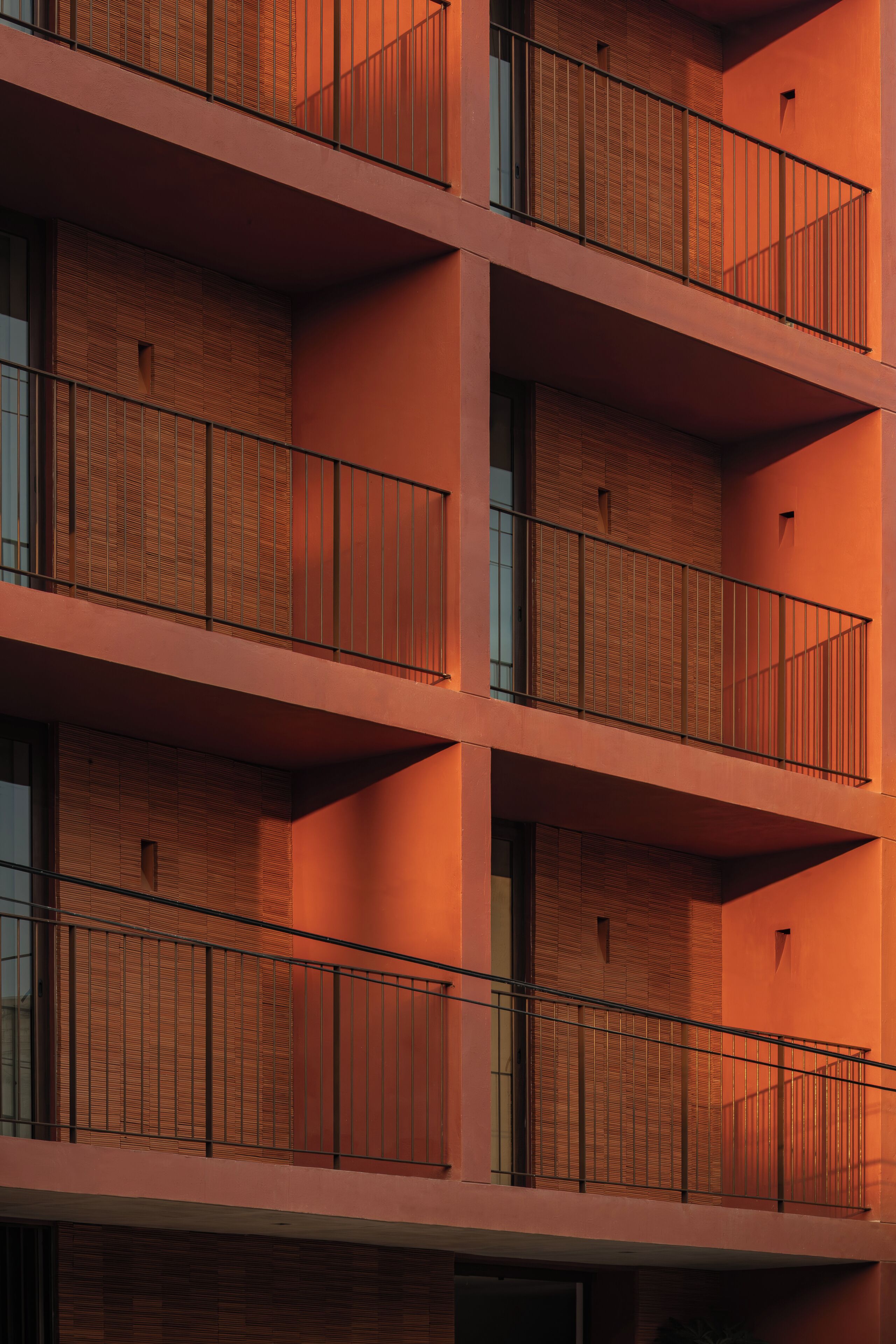 Un edificio de varios pisos con balcones y grandes ventanales.