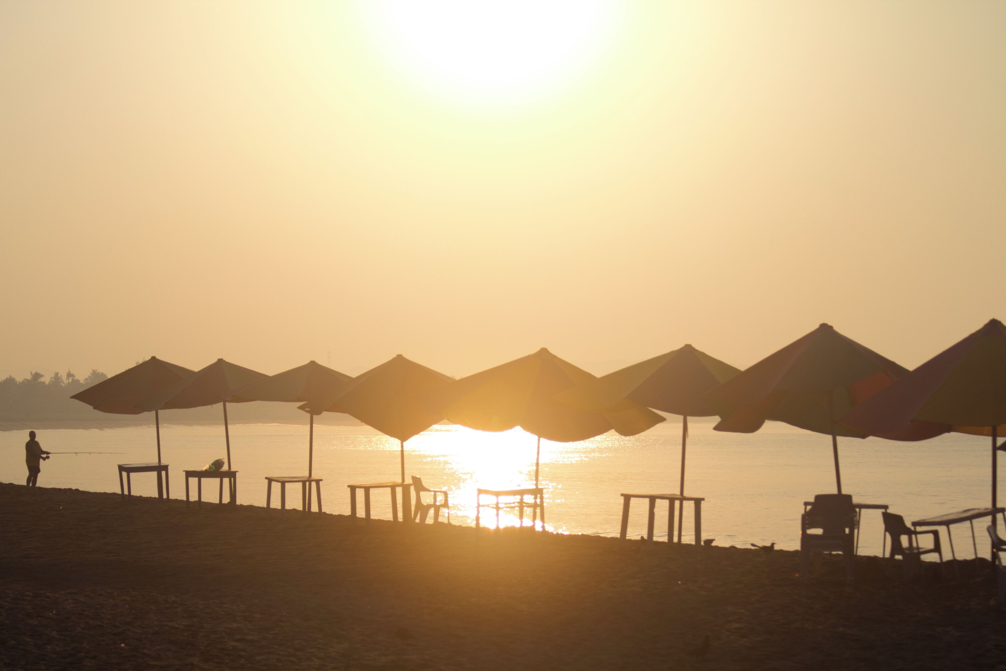 A beach with umbrellas and chairs facing the sunset.