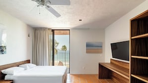 A bedroom with a bed, a TV, and a balcony with a view of the beach. - HOTEL AURELIA (San Patricio Melaque)