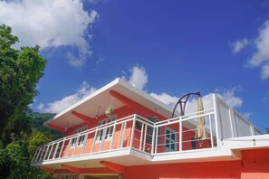 Un immeuble de deux étages doté d’un balcon et arborant une décoration aux couleurs rouge et blanche.