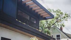 A modern house with a sloped roof, large windows, and a visible chimney.
