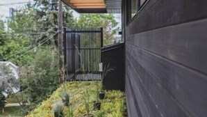 A modern building with a wooden slatted roof and a black exterior wall.