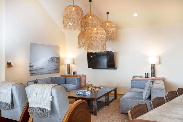 Un salon moderne avec des canapés gris, une table basse et un téléviseur fixé au mur.