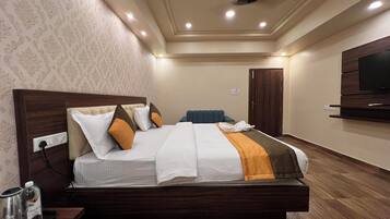 Una habitación de hotel moderna con una cama grande, cabecera de madera y un televisor de pantalla plana montado en la pared.