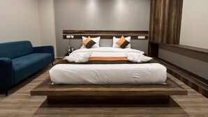 A hotel room with a large bed, a blue sofa, and a wooden headboard.