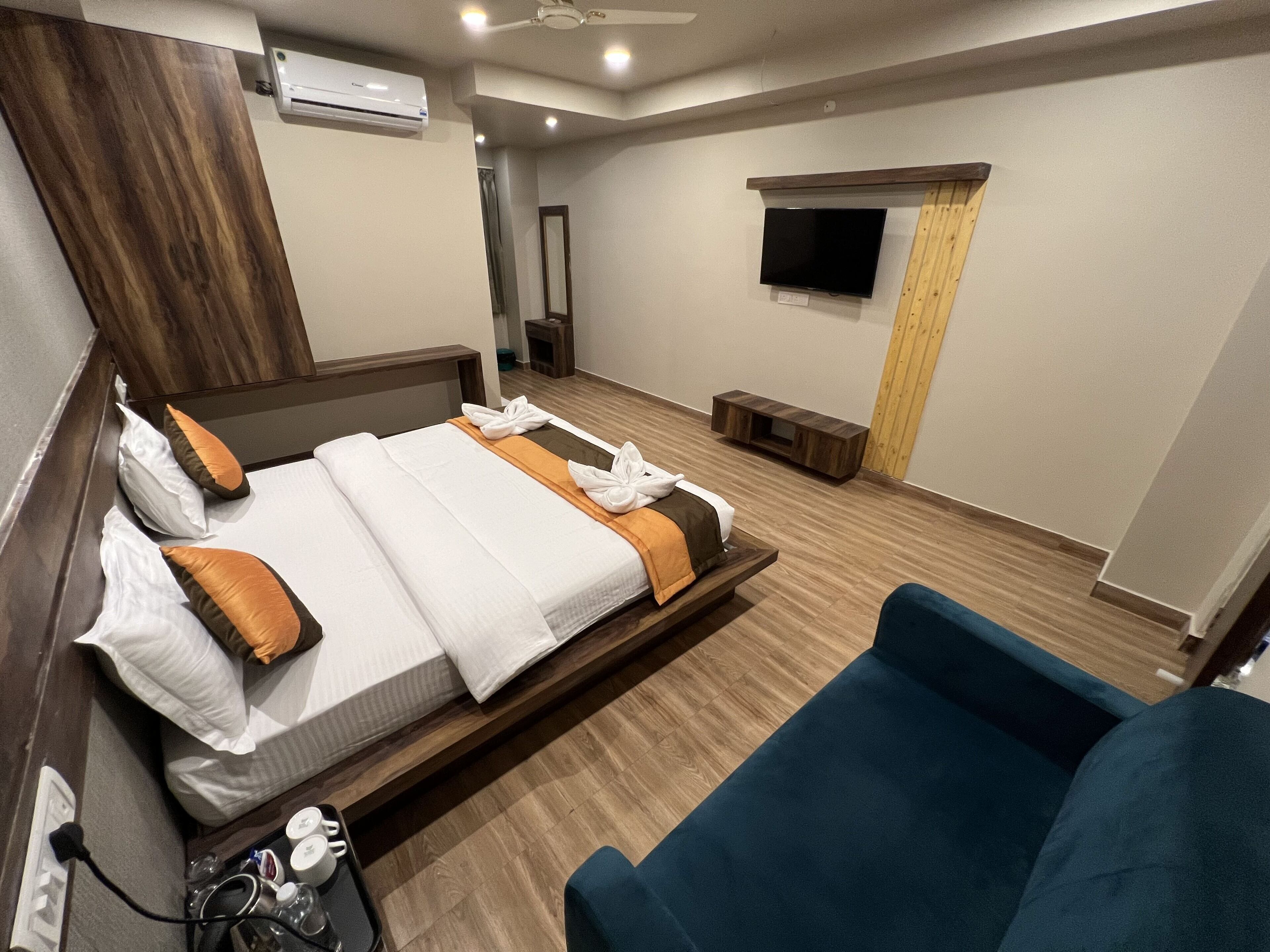 Moderni hotellihuone, jossa on suuri sänky, televisio ja oleskelualue.