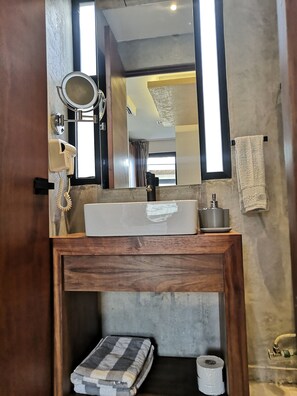 A bathroom with a wooden vanity, a sink, a mirror, a hairdryer, and a towel rack. - Nook Tulum by The Spot Rentals (Tulum)