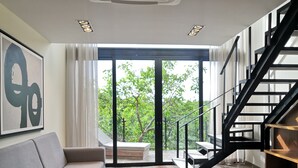 A modern living room with a sofa, a coffee table, and a staircase. - Nook Tulum by The Spot Rentals (Tulum)