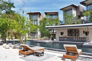 Un moderno resort con zona de piscina, sillones de descanso y vistas de los edificios circundantes.