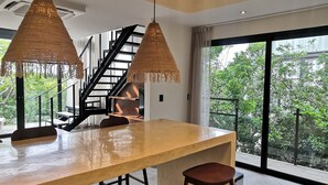 A modern kitchen with a large island, pendant lights, and a staircase leading to an upper level. - Nook Tulum by The Spot Rentals (Tulum)
