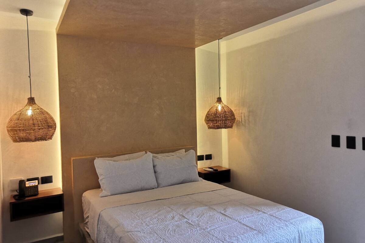 A modern bedroom with a large bed, two bedside tables, and two hanging wicker lamps.