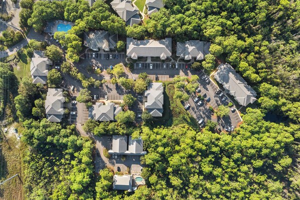 Vista aérea de uma área residencial com várias casas, uma piscina e um estacionamento.