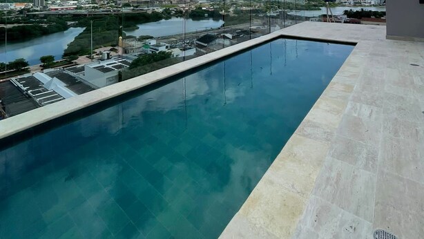 Una piscina infinita en la azotea con vistas despejadas a un paisaje urbano y un río.