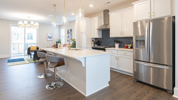 A modern kitchen with white cabinetry, stainless steel appliances, and a central island with bar stools. - Hot Tub • Game Room • Rooftop Fire Pit • Uptown (Charlotte)