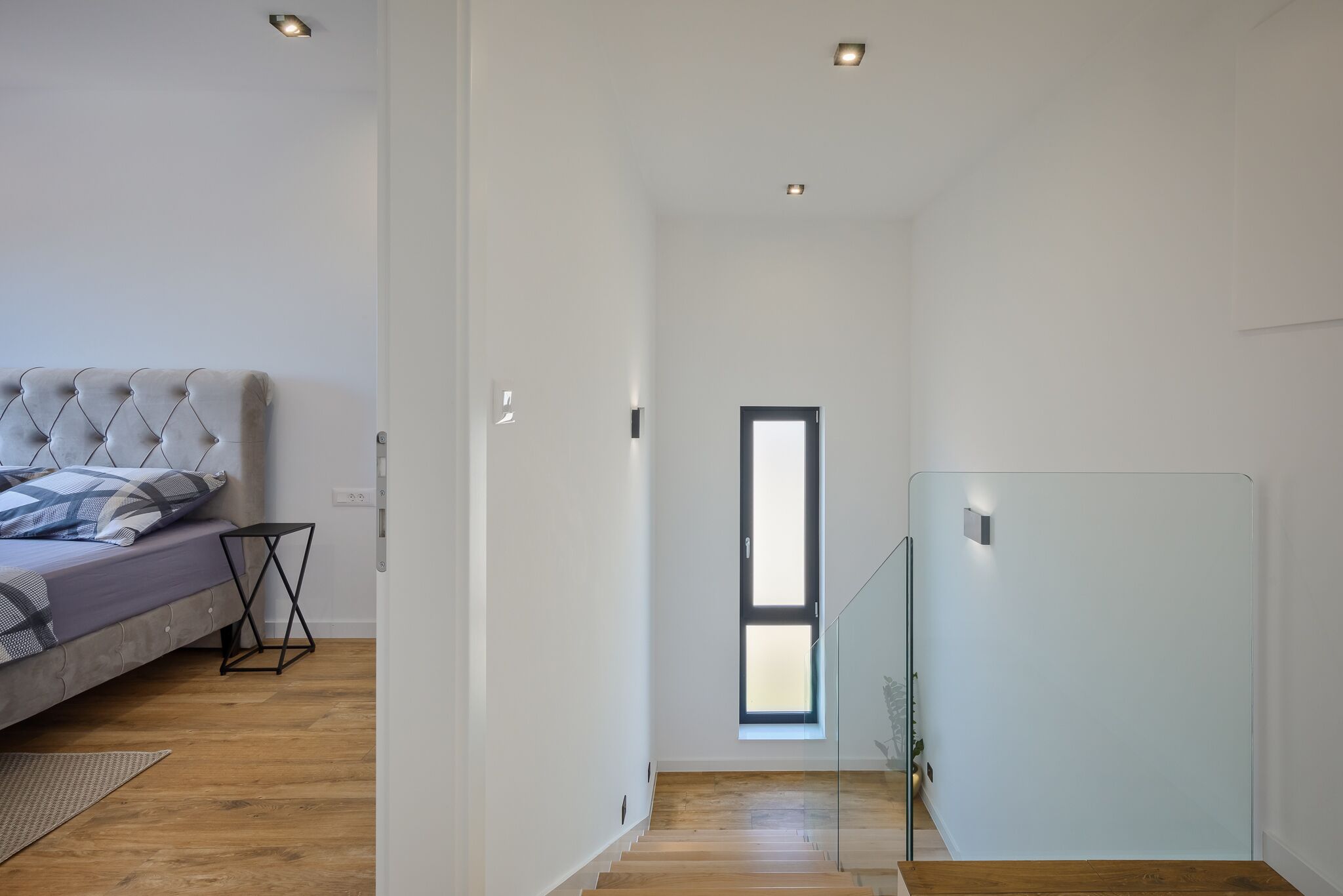 Un dormitorio moderno con una cama, una mesita de noche y una ventana.