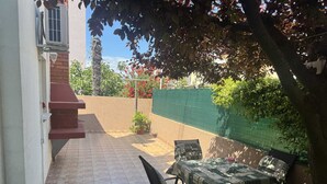 Un patio con suelo de baldosas, una mesa con sillas y una pared de ladrillo.