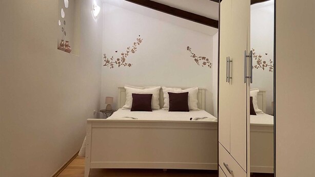 Un dormitorio con cama, mesitas de noche, armario y pegatinas decorativas en la pared.