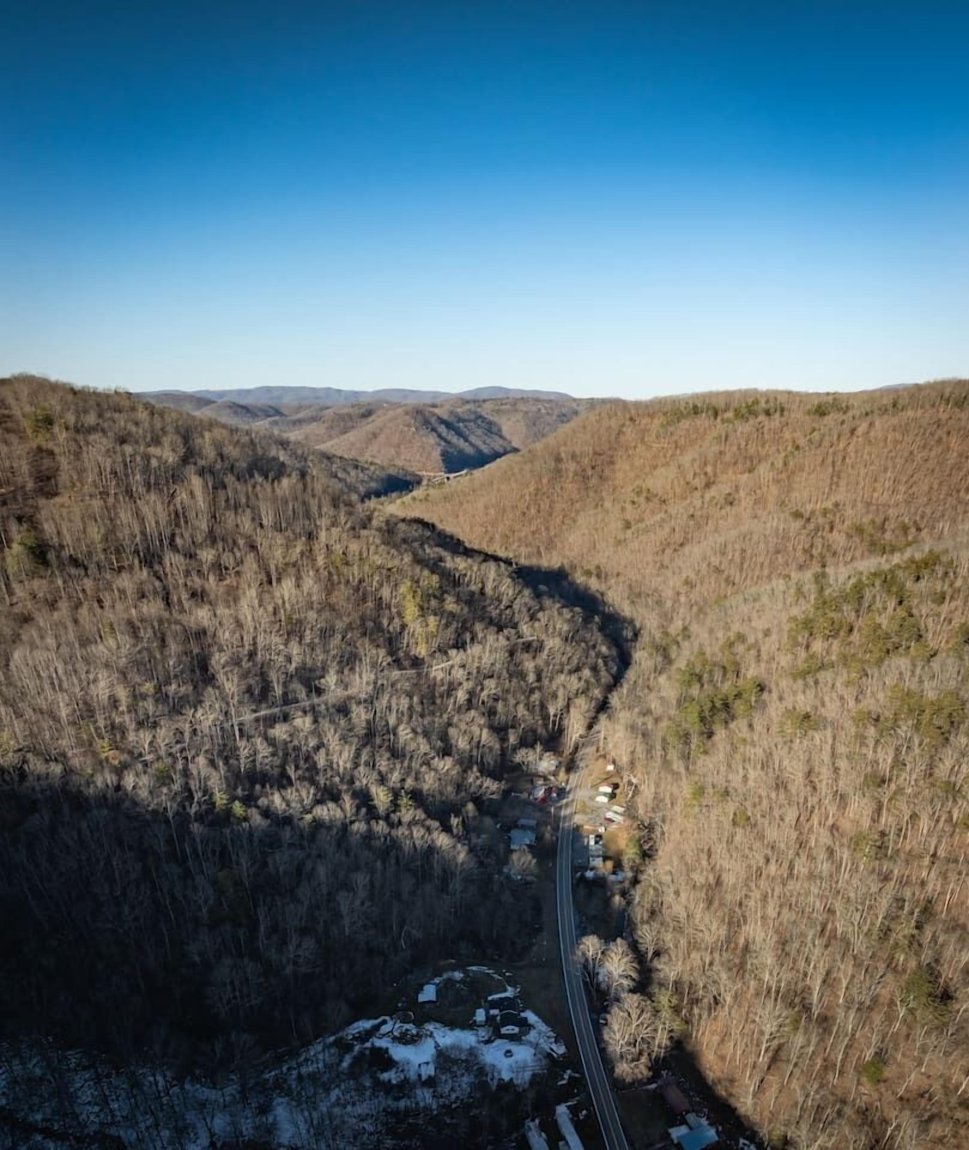 A winding road through a mountainous area with sparse vegetation and a clear blue sky.