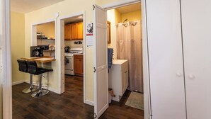 A compact kitchen with a dining area, a small bathroom, and a wardrobe. - Quaint Cabin By The Creek Privat (Pipestem)