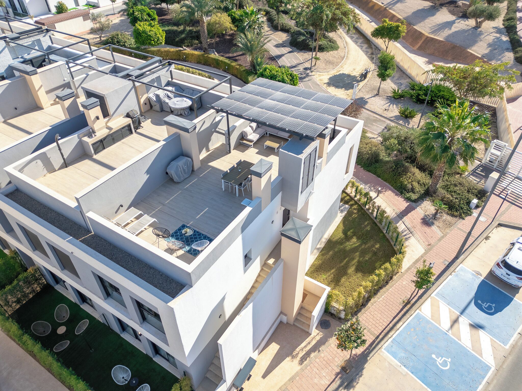 Ein modernes Gebäude mit Dachterrasse, Solaranlage und Schwimmbad.