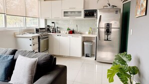 Una cocina moderna con armarios blancos, un refrigerador de acero inoxidable y una cafetera.