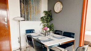 Un comedor con una mesa blanca, sillas azules y una planta en maceta.