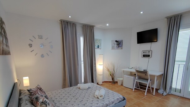 Ein modernes Schlafzimmer mit Bett, Nachttischen, Schreibtisch und Fernseher.