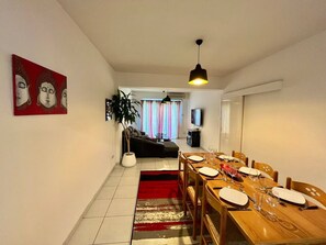 A dining area with a wooden table set for four, a red and white rug, and a modern pendant light.
