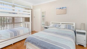 A bedroom with two bunk beds, a bedside table with a lamp, a mirror, and a framed picture on the wall. - Jack's Place - Cozy Retreat (Gerringong)