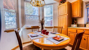 A dining area with a round wooden table, chairs, and a chandelier.