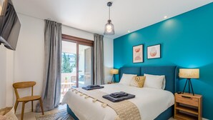 Quarto moderno com uma cama grande, televisão e vista para o exterior.