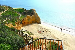 A coastal beach with a wooden staircase leading down to the shore, a sandy beach, and a clear view of the ocean. - Balaia Apartment at Albufeira (Albufeira)