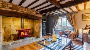 Una habitación acogedora con chimenea de piedra, un teléfono público, un sofá con un cojín de zorro y una mesa de centro de cristal.