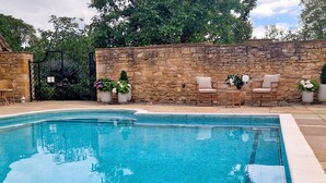 Una piscina con paredes de piedra y mobiliario exterior.