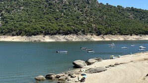 Una spiaggia con barche, persone e una collinetta rocciosa sullo sfondo.