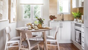 Una cucina moderna con mobili bianchi, un tavolo da pranzo rotondo e sedie, e un lampadario intrecciato.
