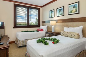 A hotel room with two beds, a desk, a chair, a lamp, and a window with blinds.