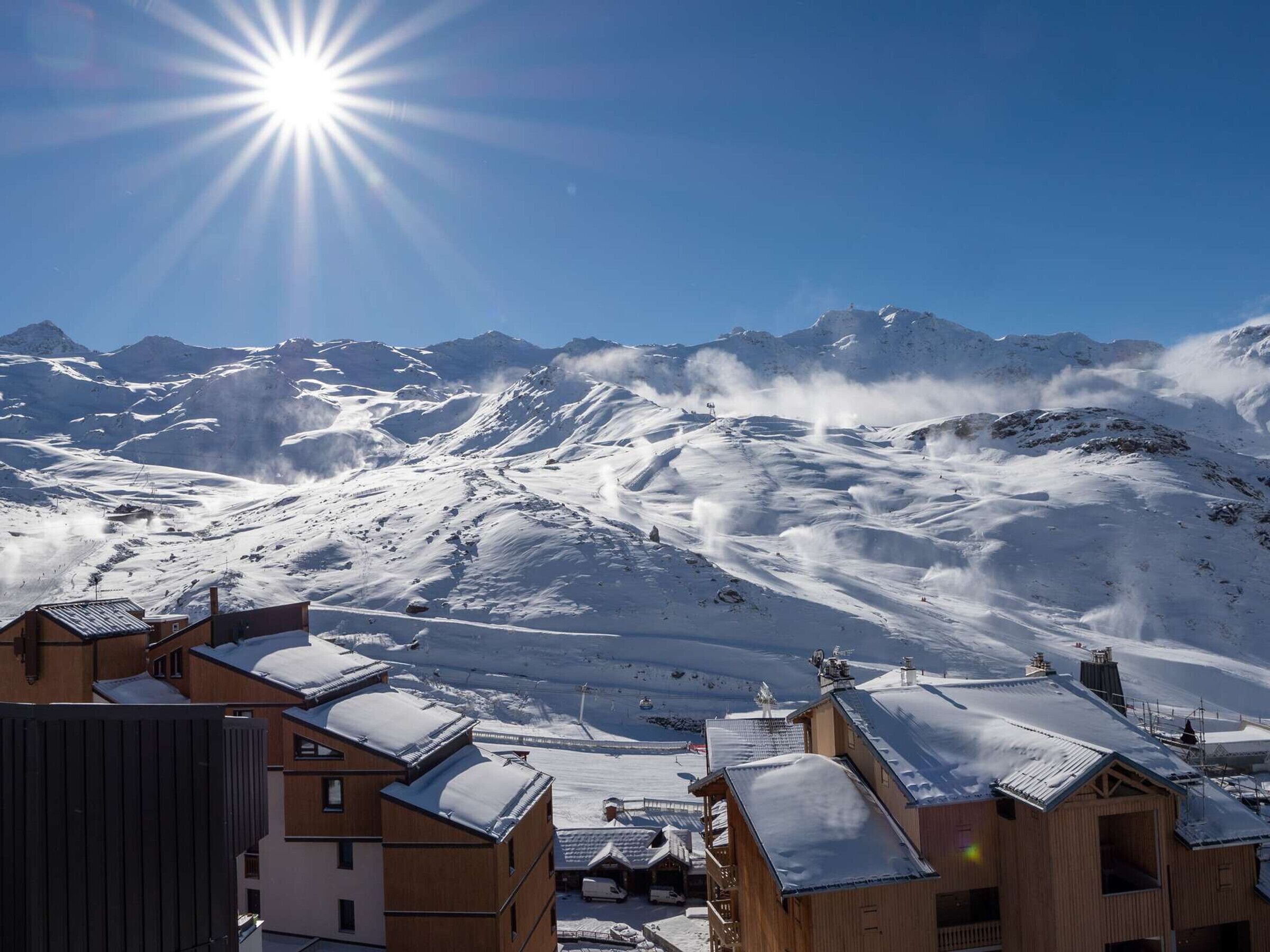 Paesaggio montano innevato con edifici in primo piano.