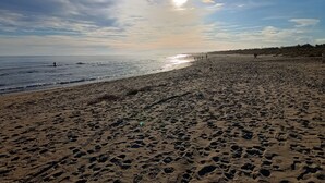 En strand med fodaftryk og en klar himmel.
