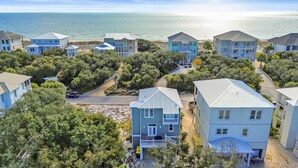 Een kustgebied met woonhuizen, meerdere tweelaagse woningen, een weg en een strand op de achtergrond.