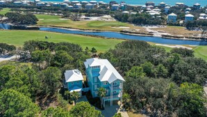 A coastal property with a golf course, a body of water, and a large house surrounded by trees. - Tropical Holiday house at Kiva Dunes (Gulf Shores)