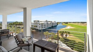 Un balcon avec vue sur une rivière, un terrain de golf et un grand bâtiment d’hôtel.