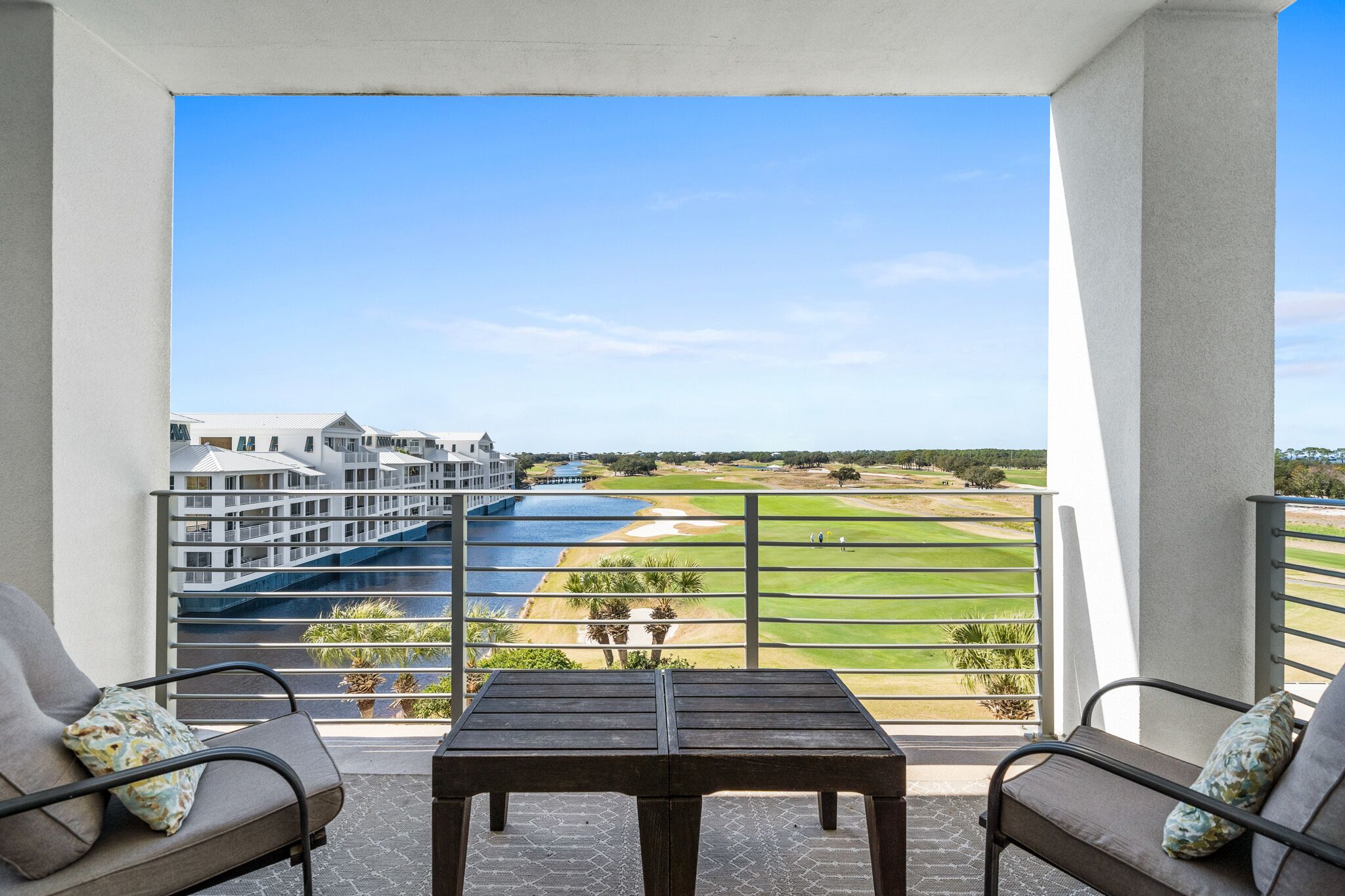 Ein Balkon mit Blick auf einen Golfplatz, ein Schwimmbad und ein mehrstöckiges Gebäude.