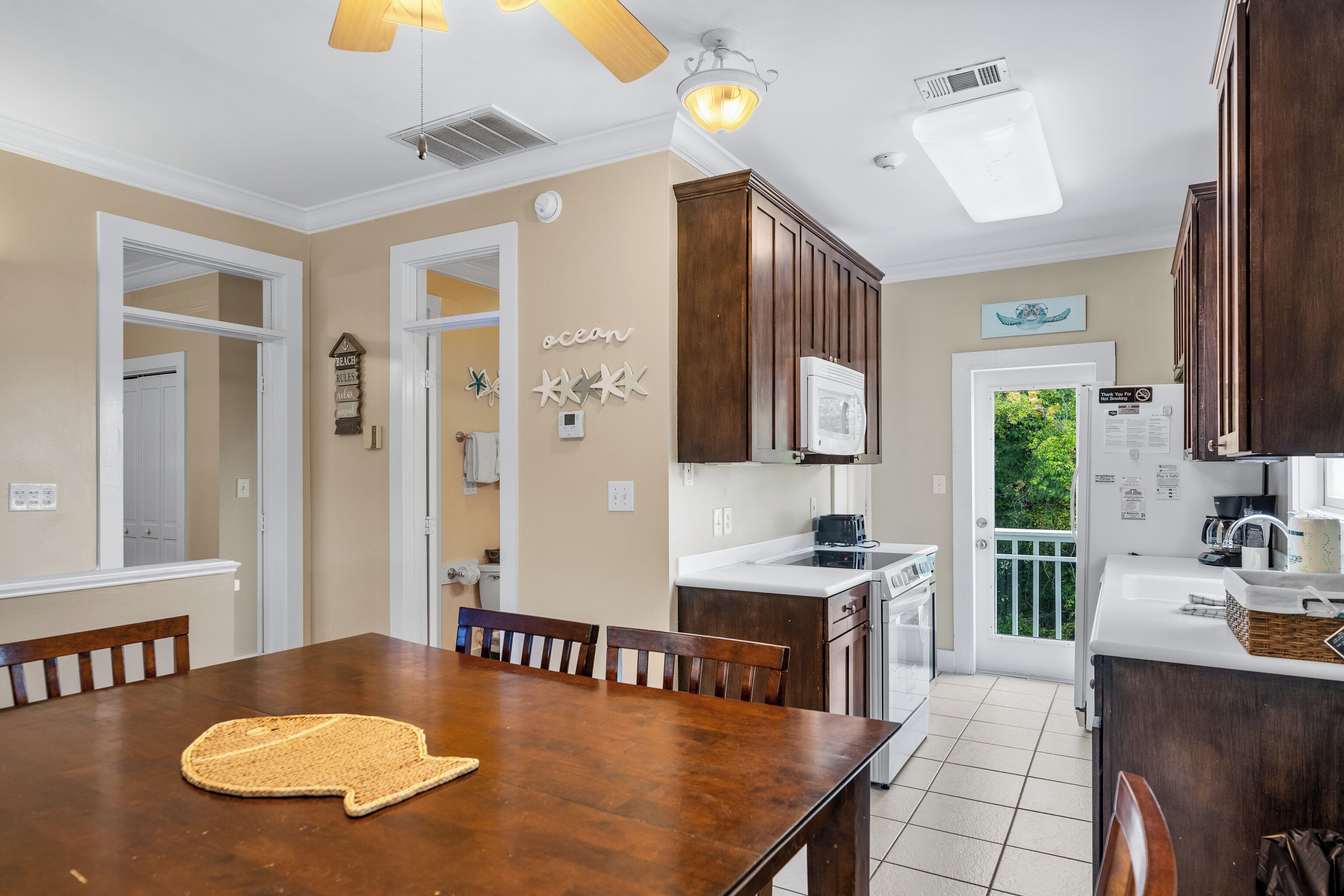 Une cuisine avec des meubles en bois, une table à manger et un ventilateur de plafond.