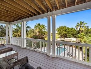 A covered outdoor area with a pool, white railings, and wicker furniture. - Our Hangout house at Kiva Dunes (Gulf Shores)