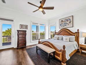 Um quarto com cama de madeira, um banco, cômoda e ventilador de teto.