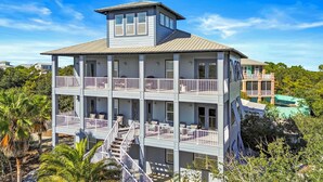 A multi-story building with balconies, a central staircase, and a view of surrounding greenery. - Seabiscuit house at Kiva Dunes (Gulf Shores)